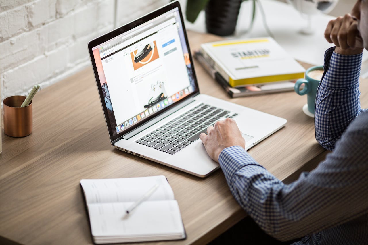 A person working on a laptop at a wooden desk